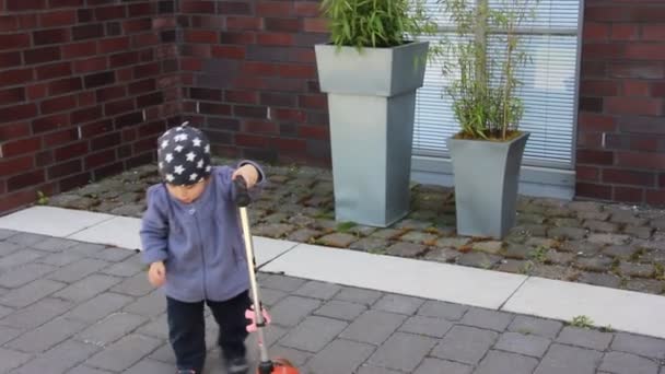 Liten flicka försöker rida en stor scooter — Stockvideo