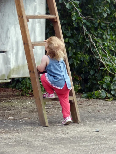 Portret van klein schattig blond meisje op de houten trap — Stockfoto
