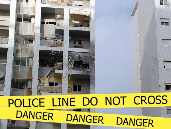 Полицейская линия не пересекаются подписать ленту на поврежденном фоне взрыва здания — стоковое фото