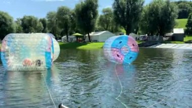 Münih, Bavyera, Almanya. Olimpiyat parkı. Çocuklar için eğlence, lunapark gezileri. Yüzen plastik su varilleri. Çocuklar zorlaşıyor. 4K