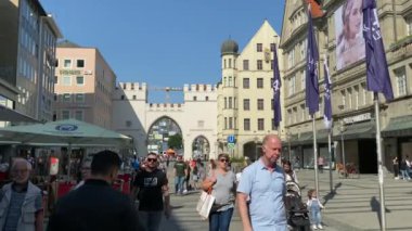 Münih, Almanya - 06 Ağustos 2021: Ortaçağ şehir kapılarıyla Neuhauser Caddesi (strasse) - Charles kapısı. İnsanlar Münih 'in en işlek ve en popüler alışveriş caddesi olan Kaufinger Caddesi boyunca yürüyüp alışveriş yapıyorlar.
