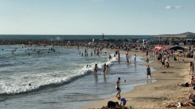 Tel Aviv, İsrail - 26 Mayıs 2021: Tel Baruch sahilinde tanınmayan erkek ve kadınlar, yerel halk için favori tatil yeri. 4K