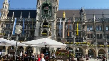 Münih, Almanya - 14 Ağustos 2021: Marienplatz Meydanı 'ndaki belediye binasının önündeki turistler. Mary 'nin meydanı ve güneşli bir günde New Town Hall. 4K