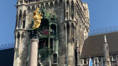 Münih, Almanya. Marienplatz 'da (Mary' nin meydanı) New City Hall (Neues Rathaus) önünde ünlü Marian Sütunu. Carillon (Glockenspiel) müzik. Güneşli bir günde sesli video. 4K