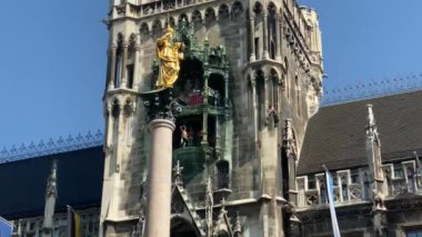 Münih, Almanya. Marienplatz 'da (Mary' nin meydanı) New City Hall (Neues Rathaus) önünde ünlü Marian Sütunu. Carillon (Glockenspiel) müzik. Güneşli bir günde sesli video. 4K