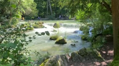 Münih, Bayern, Almanya 'daki İngiliz bahçesinde bir dere manzarası. Gerçek sesli video. 4K