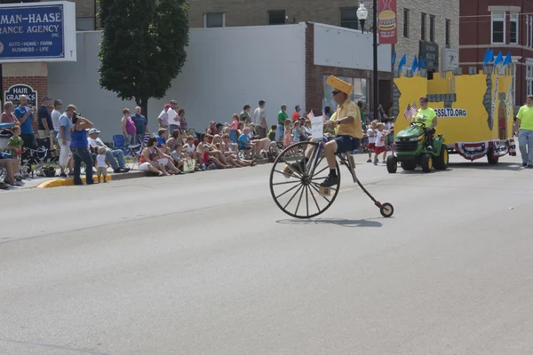 Man met cheesehead hoge wiel fiets — Stockfoto