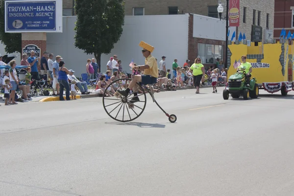 Man met cheesehead hoge wiel fiets in parade — Stockfoto