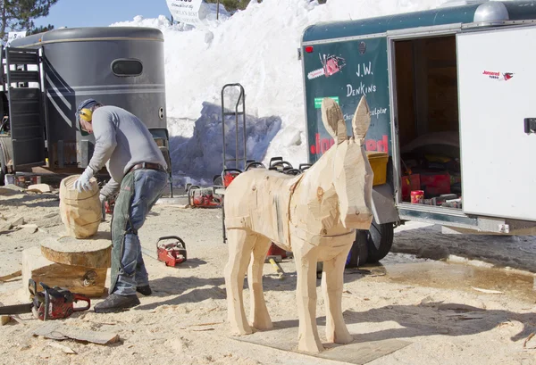 Man using Chainsaw to carve a donkey wood carving — Stock Photo, Image