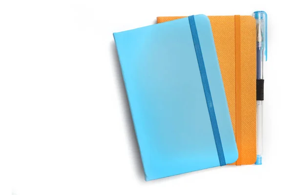 Μπλε Και Πορτοκαλί Σημειωματάρια Και Ένα Στυλό Λευκό Φόντο — Φωτογραφία Αρχείου