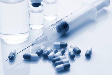 Şırınga hapları ve beyaz arka planda birkaç şişe. Duotone resmi.