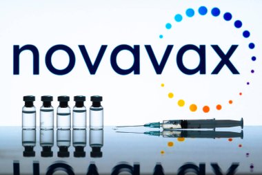 Carrara, İtalya - 23 Aralık 2021 Novavax aşı logosu bazı şişeler ve ön planda bir şırınga