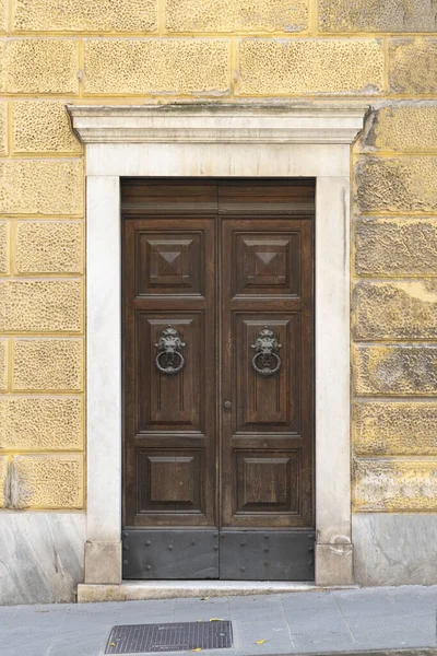 Ancient wooden door with Italian marble portal on a yellow renaissance building