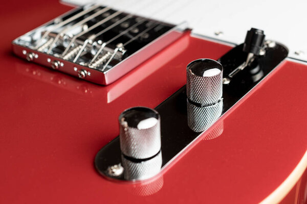 Red guitar control plate and bridge with selective focus on the volume knob