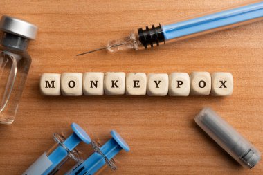 Monkeypox pandemic concept: dice surrounded by syringes and vials make up the word monkeypox clipart