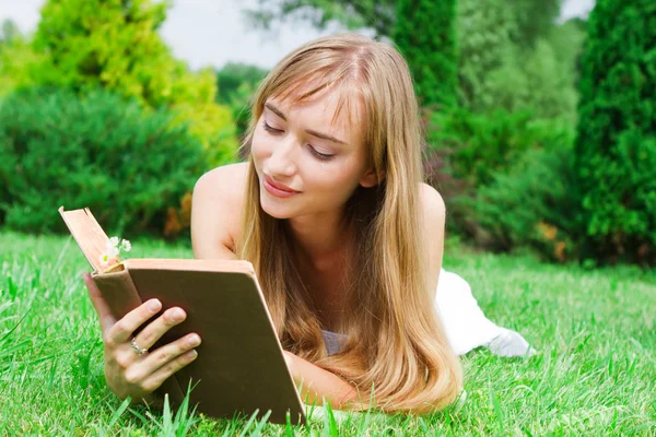 Close-up portrait of a young woman with a book on the grass — Stock Photo, Image