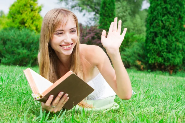 Close-up πορτρέτο του μια νεαρή γυναίκα με ένα βιβλίο στο γρασίδι — Φωτογραφία Αρχείου