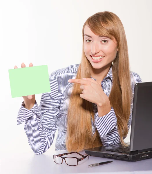 Portrait of a young businesswoman holding a blank card near lapt — Stock Photo, Image