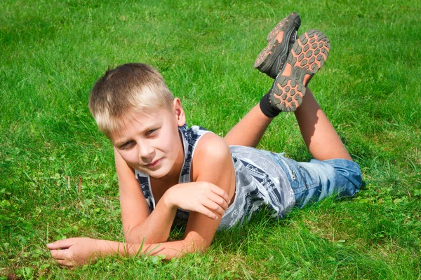 Menino feliz deitado na grama ao ar livre — Fotografia de Stock