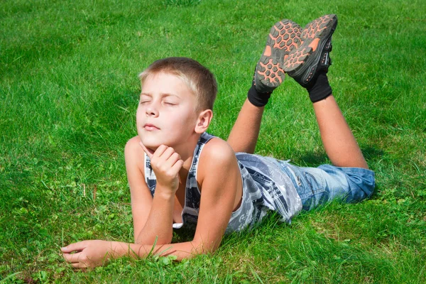 屋外の芝生の上に横たわって、幸せな少年 — ストック写真