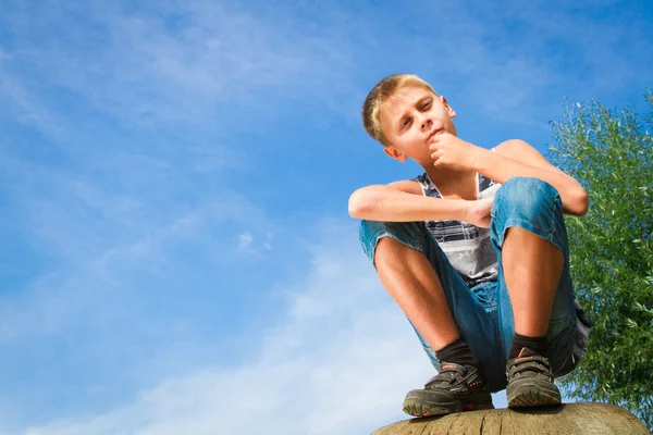 Glücklicher Junge sitzt auf einem Baumstumpf — Stockfoto