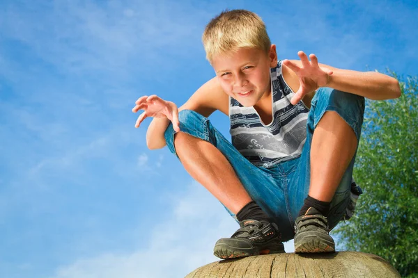 Glücklicher Junge sitzt auf einem Baumstumpf — Stockfoto