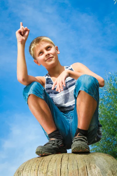 Glücklicher Junge sitzt auf einem Baumstumpf — Stockfoto