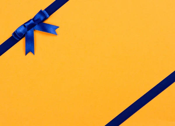Blue ribbon bow on yellow background — Stock Photo, Image