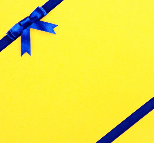 Blue ribbon bow on yellow background — Stock Photo, Image