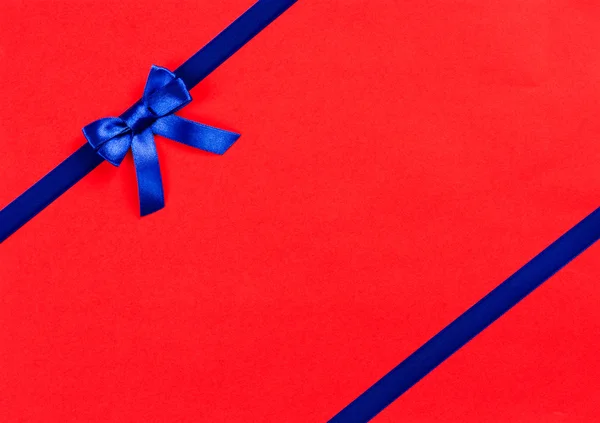 Blue ribbon bow on red background — Stock Photo, Image