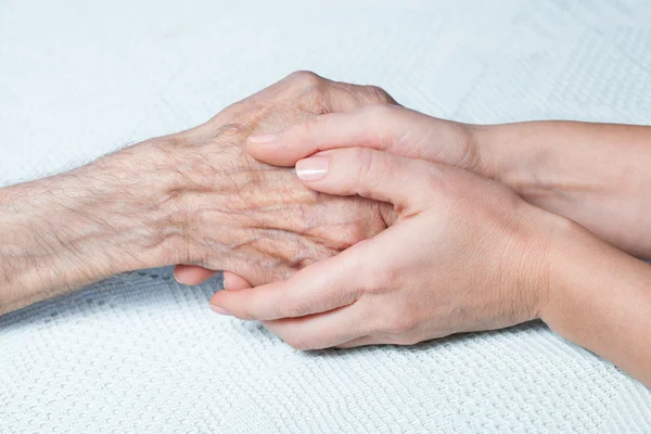 A young girl holds hands of an old man. — Stock Photo, Image