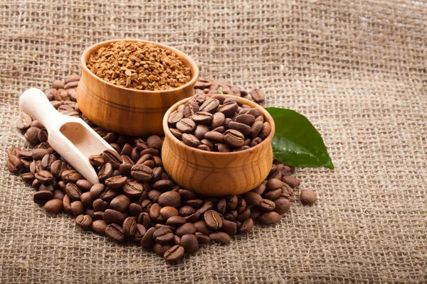 Kávová zrna v dřevěné misce na pytlovina pozadí — Stock fotografie