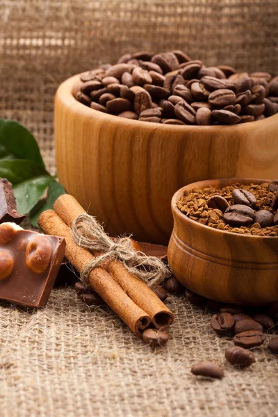 Granos de café en un tazón de madera sobre fondo de arpillera —  Fotos de Stock