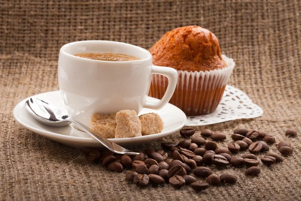 Чашка кави, зерна на тлі мішковини — стокове фото