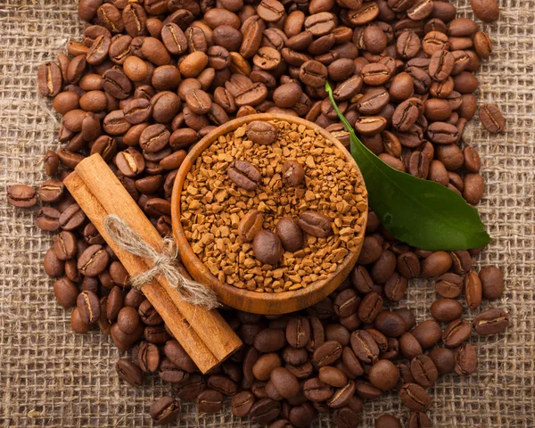 Granos de café en un tazón de madera sobre fondo de arpillera — Foto de Stock