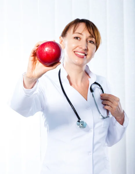 Femme médecin donnant pomme rouge — Photo