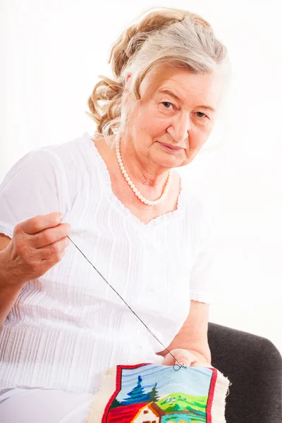 Portrait of an old woman engaged in needlework — Stock Photo, Image