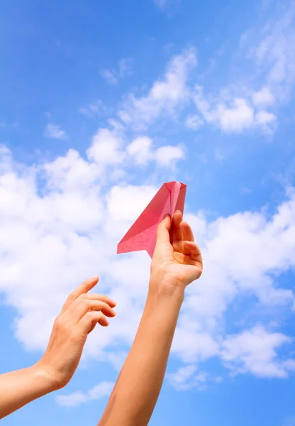 Woman starts paper plane in blue sky. — Stock Photo, Image