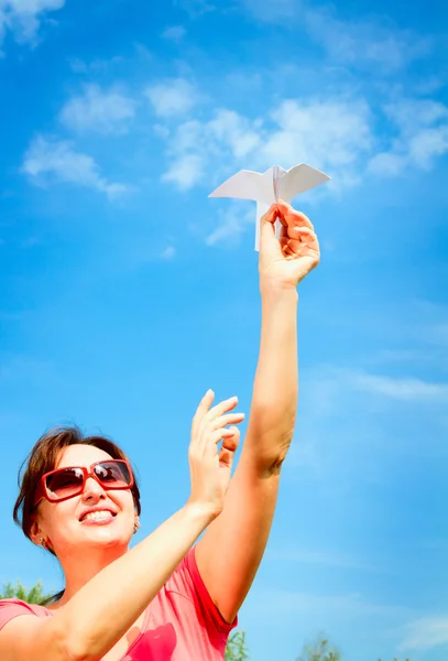 Woman starts paper plane in blue sky. — Stock Photo, Image