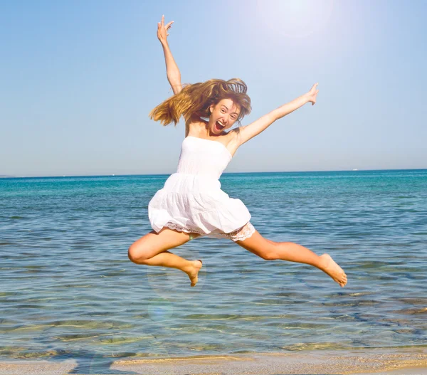 Счастливая молодая красивая женщина прыгает на пляже Лицензионные Стоковые Фото
