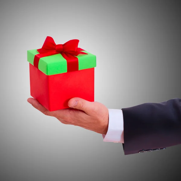 Businessman holding gift box with red bow — Stock Photo, Image