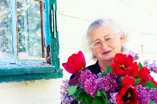 Portret starsza kobieta z kwiatami — Zdjęcie stockowe