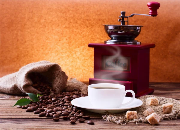 Cup of warm coffee and grinder. — Stock Photo, Image