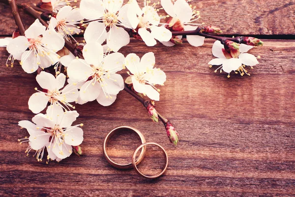 Anillos de boda. Rama floreciente flores sobre superficie de madera . — Foto de Stock