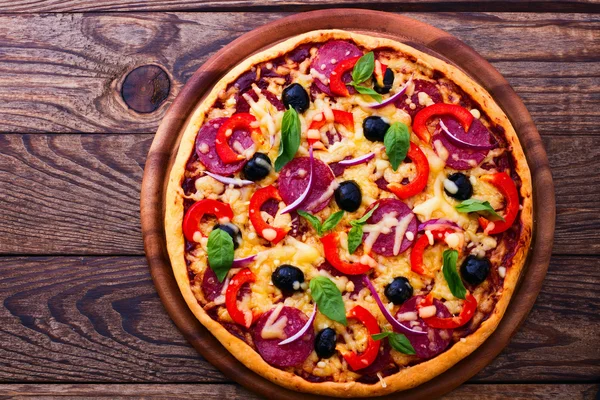 Pizza med skinka, paprika och Oliver. läckra färsk pizza serveras på träbord. — Stockfoto