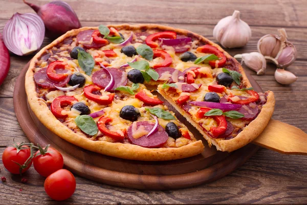 Pizza con jamón, pimienta y aceitunas. Deliciosa pizza fresca servida en mesa de madera . —  Fotos de Stock