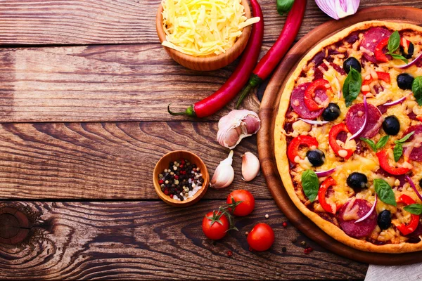 Pizza dengan ham, lada dan zaitun. Pizza segar lezat disajikan di atas meja kayu . — Stok Foto