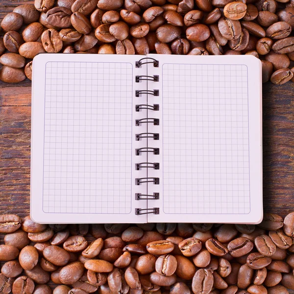 Notebook puro para menu, registro de receita em mesa de madeira vista superior. Grãos de café como fundo — Fotografia de Stock