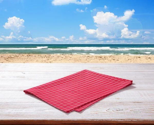 木制桌子上空的红色桌布 上面有餐巾纸顶视图模型 海滨背景 — 图库照片
