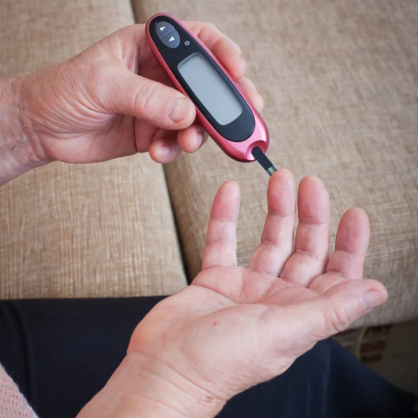 血糖値を確認するシニア女性はGlucometerを使用して 糖尿病の高齢者のクローズアップ手 高齢者糖尿病治療 — ストック写真